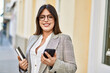© Krakenimages.com - Young hispanic businesswoman smiling happy using smartphone at the city.