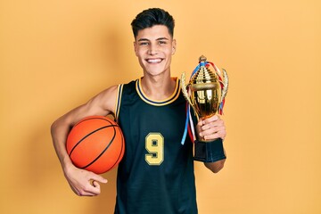 Sticker - Young hispanic man wearing basketball uniform holding ball and prize smiling with a happy and cool smile on face. showing teeth.