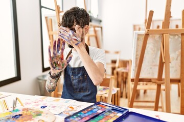 Poster - Hispanic man with beard at art studio covering eyes with hands and doing stop gesture with sad and fear expression. embarrassed and negative concept.