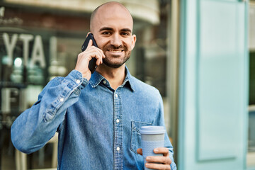 Poster - Young hispanic man talking on the smartphone and drinking coffee at the city.