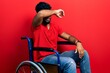 Arab man with beard sitting on wheelchair covering eyes with arm, looking serious and sad. sightless, hiding and rejection concept