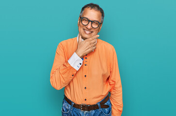 Canvas Print - Middle age indian man wearing casual clothes and glasses looking confident at the camera smiling with crossed arms and hand raised on chin. thinking positive.