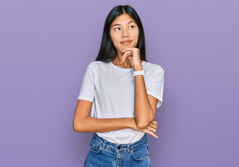 Sticker - Beautiful young asian woman wearing casual white t shirt with hand on chin thinking about question, pensive expression. smiling and thoughtful face. doubt concept.