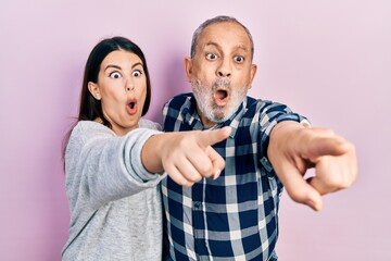 Wall Mural - Hispanic father and daughter wearing casual clothes pointing with finger surprised ahead, open mouth amazed expression, something on the front