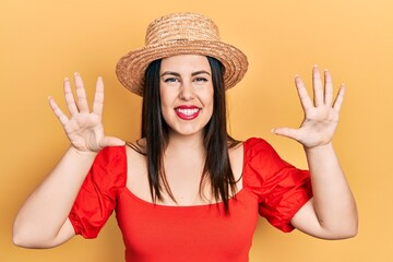 Sticker - Young hispanic woman wearing summer hat showing and pointing up with fingers number ten while smiling confident and happy.