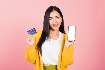 Wall Mural - Happy Asian portrait beautiful cute young woman excited smiling hold mobile phone and plastic debit credit bank card, studio shot isolated on pink background, female using smartphone online shopping