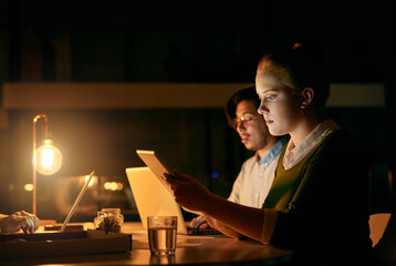 Leinwandbilder - It will all get done tonight. Shot of a young businesswoman working on a digital tablet in an office at night.