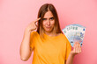 © Asier - Young caucasian woman holding banknotes isolated on pink background showing a disappointment gesture with forefinger.