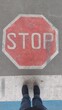 © Stihl024 - 2 Füße in Jeans stehen still vor auf der Straße aufgemaltem Stopp-Schilod