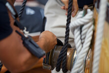 Sailor's Hand Adjusting Ropes To Hoist The Sails Of A Sailboat - Adventure, Travel Concept