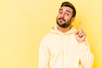 Young caucasian man isolated on yellow background showing number one with finger.