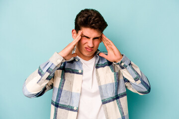 Young caucasian man isolated on blue background having a head ache, touching front of the face.