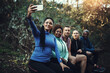 © Thurstan Hinrichsen/peopleimages.com - We love taking selfies during our workout. Cropped shot of a sporty young group of friends taking a selfie while taking a break during a workout in the forest.