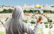 Rear view of a hooded person throwing stones at a metal balla in jerusalem