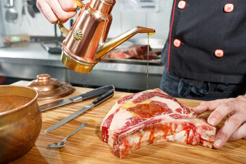 Wall Mural - chef preparing aged meat, t bone on wooden table, pouring oil on kitchen background, steak concept