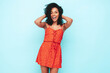 © halayalex - Portrait of beautiful black woman with afro curls hairstyle. Smiling model dressed in red summer dress. Sexy carefree female posing near blue wall in studio. Tanned and cheerful