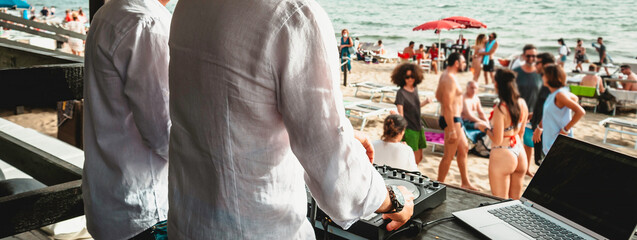 Horizontal banner or header with disc jockeys playing music for tourist people at club party outdoors on the beach - Djs wearing headphones at music live event - Music and fun concept