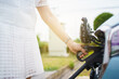 © DG PhotoStock - Unrecognizable Asian woman holding aa DC - CCS type 2 EV charging connector at EV charging station.