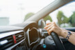 © DG PhotoStock - Unrecognizable female driver using left hand grabs on the steering wheel while driving on the road.