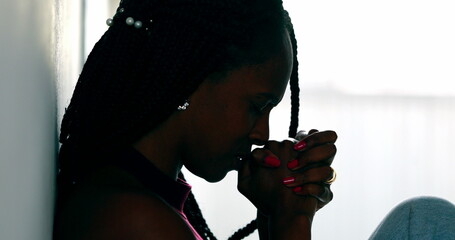 Hopeful woman praying that life will get better. Black African female prayer