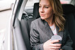 © bugarskipavle3 - A business woman drinks coffee in the back seat of a car.