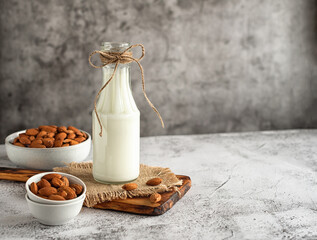 Almond milk in a glass bottle and almonds on a gray marble table. Horizontal photo. Copy space. Top view.