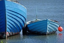 A Large Blue Painted Fishing Boat With A Small Blue Boat Moored Next To It In A Fishing Harbour.