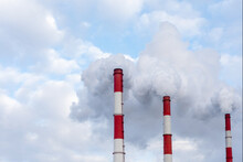 Three Chimneys With A Lot Of Toxic Smoke Against A Blue Sky
