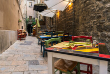 Tables And Chairs In A Narrow Alley, Trattoria In Italy