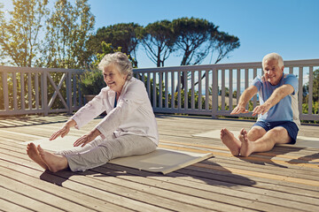 Sticker - Keeping lithe and limber. Shot of a senior couple doing yoga together on their patio outside.