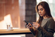 © Zamrznuti tonovi - Woman using smartphone and a credit card for online shopping in a cafe