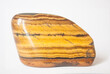 Beautiful semi-precious stone jasper in gold color. Macro. Mineral with orange-yellow drawing. Single stone in white background with shadow.