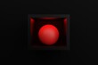 © Sebastian - A red sphere in a frame illuminated by red light on a black background. Concept of abstract figures as a background. 3D rendering, 3D illustration.