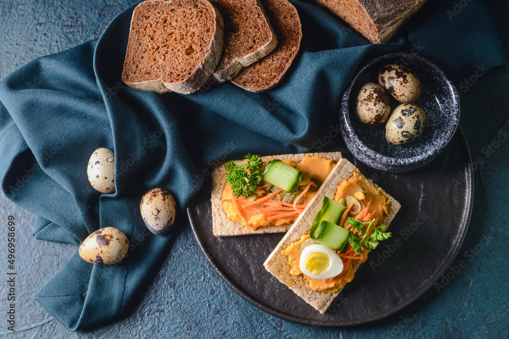Plate with crispbreads and tasty hummus on dark background