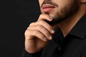 Wall Mural - Man with stylish manicure touching his face on black background, closeup