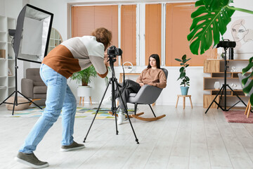 Wall Mural - Photographer taking picture of female model in modern studio