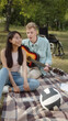 © iaginzburg - A disabled young guy in a blue shirt is playing guitar and singing songs for his girlfriend in tha park