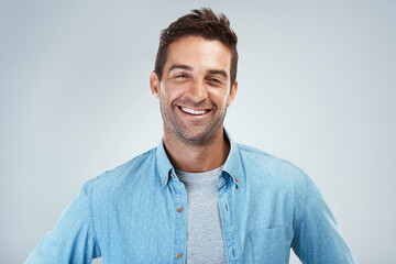 Wall Mural - Always a cheerful one. Portrait of a cheerful young man smiling brightly while standing against a grey background.