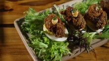 Elegantly Plated Deviled Eggs Topped With Fried Oysters And Aioli Sitting On Field Greens, Slider Close Up 4K
