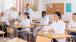 © JackF - Portrait of focused female sitting at desk studying in classroom with colleagues medicals during training program for health workers