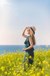 © Yido - A young woman on the seashore in Jeju Island, South Korea. Rape flowers.