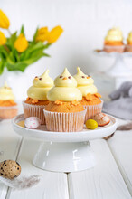 Cute Easter Chick Cupcakes. Vanilla Cupcakes With Buttercream On A White Stand With Fresh Flowers On A White Wooden Background. Copy Space.