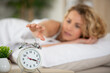 young woman is waking up with alarm clock