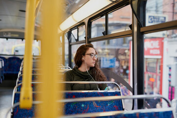 Wall Mural - Shes on her way. High angle shot of an attractive young woman listening to music while sitting on a bus.