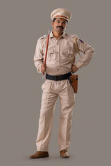 Wall Mural - Portrait of an Indian policeman posing with baton and hands on waist