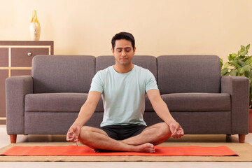 Wall Mural - Portrait of a young man meditating at home