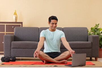 Wall Mural - Male Indian Yoga instructor conducting an online class with laptop