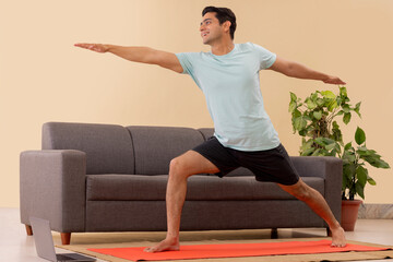 Wall Mural - Male Indian Yoga instructor conducting an online class with laptop