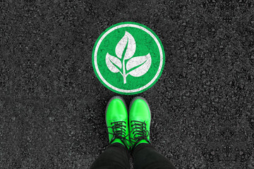 a woman with a boots is standing next to plant sign on road asphalt
