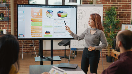 Wall Mural - Company workers planning business presentation, collaborating on graphs and charts to research financial growth. Diverse team of partners meeting in boardroom for executive cooperation.